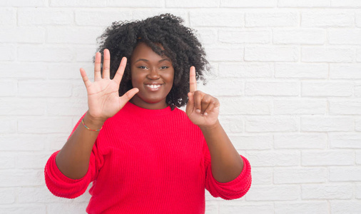 黑发西班牙裔女孩显示和指向手指数六, 而微笑着自信和快乐灰色垃圾