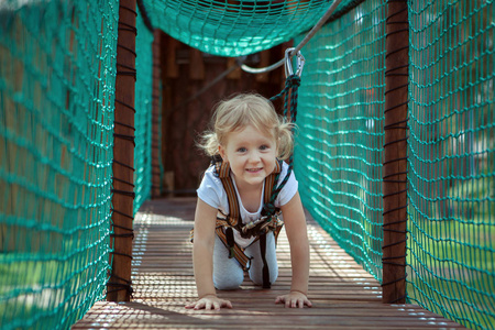 小金发女孩克服了绳索公园的障碍。她在爬行