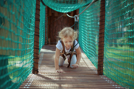 小女孩克服了绳索公园的障碍物。她在爬行