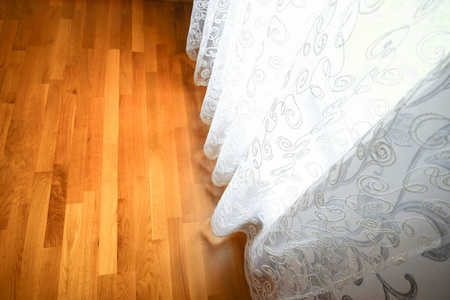 木地板和窗帘。光窗帘碰到了棕色镶木地板的表面