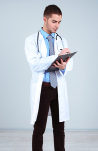 男医生站与灰色的背景上的文件夹