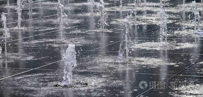 在露天的小美丽的喷泉, 在街上。水滴, 水中的喷气机在空中被冻结在飞行的背景下。夏日