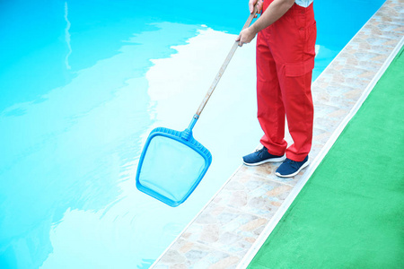 男工人清洁户外泳池与铲网