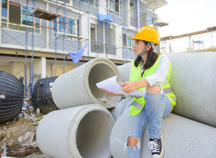 在建筑工地举行蓝图的女工程师