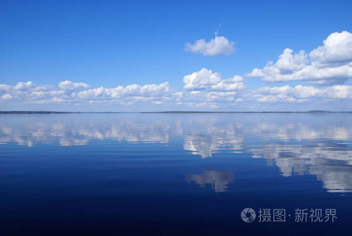 美丽的平静的蓝色湖与反射白云在水中.天气晴朗, 晴天.天空是蓝色的.