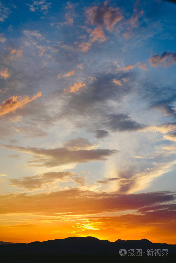 美丽的日落与阳光的橙色色调的山后, 深蓝色的天空