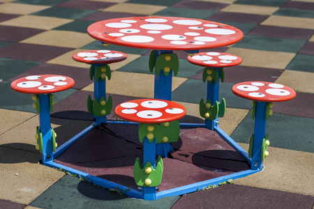 特写镜头五颜六色的新圆形儿童小桌子和五凳子户外在广场橡胶地板上幼儿园操场上。游戏休息和娱乐场所