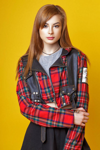 一个可爱的年轻的亚洲女孩, 红色的头发, 穿着格子夹克, 裙子和紧身裤摆在工作室的黄色背景