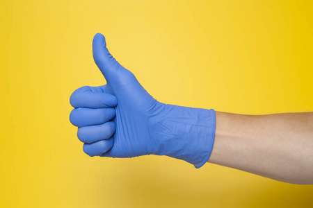 手在蓝色手套孤立的黄色与拇指向上
