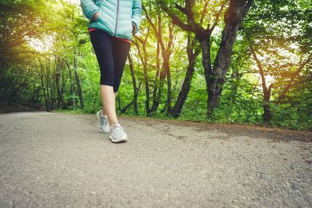 在森林里慢跑之前, 一个穿着紧身裤和运动鞋的运动女孩的脚步特写。户外运动的概念
