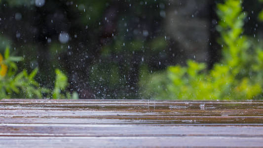 雨点落在一个木制的露台和靠近游泳池的一座桥附近