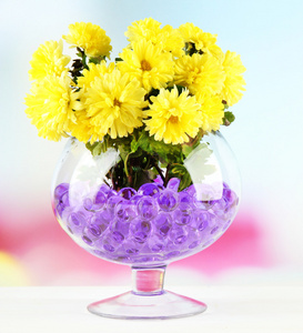 美丽的鲜花在水凝胶在明亮的背景上桌上的花瓶