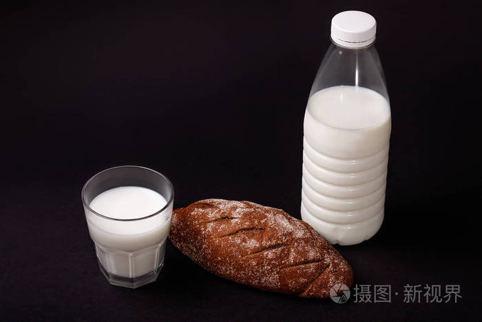 黑暗背景下的一瓶牛奶和自制黑面包