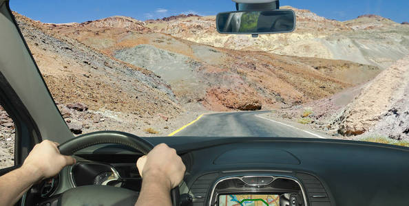 在加州的死亡谷, 在岩石中驾驶一辆汽车向一条偏僻的道路驶去