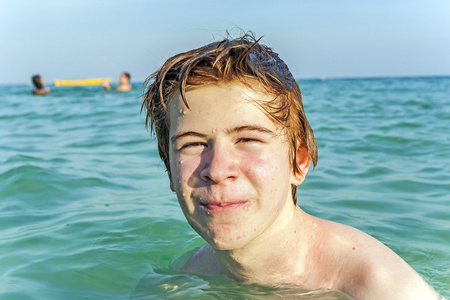 红头发的男孩享受清澈温暖的海水
