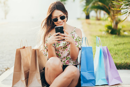 购物女人用智能手机和手提袋购物