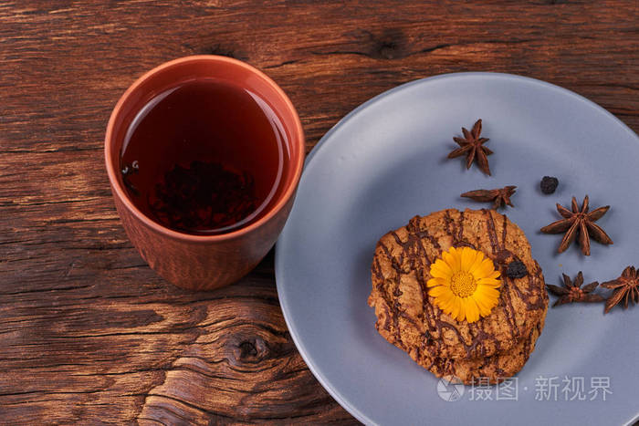 木桌上的黄色花杯红茶和巧克力coockies