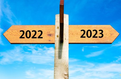 与两个相对的箭头，在湛蓝的天空 2022年和 2023 年标志 新年快乐概念形象的木制路标