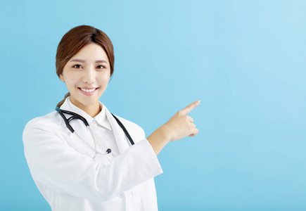 微笑的女性医生指向蓝色背景手指