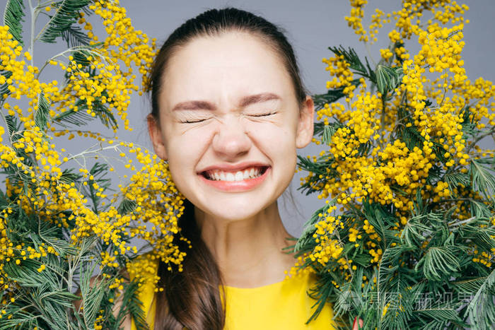 滑稽的小女孩微笑着闭上眼睛捧着一只黄色的含羞草