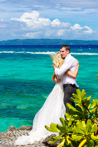 幸福的新娘和新郎在 p 下的热带海滩上玩乐