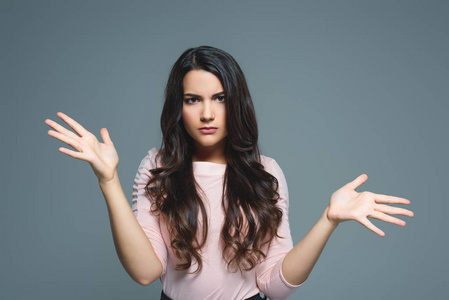 美丽的困惑的女孩耸耸肩手势, 孤立的灰色照片