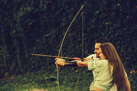 男人和漂亮女人用弓和箭射击可爱的女孩和英俊的男人用弓和箭射击射箭