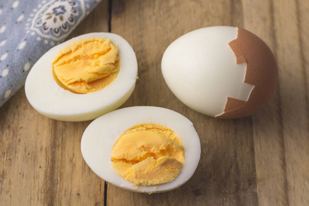 在质朴的木桌上隔离的煮鸡蛋选择性地聚焦在煮鸡蛋片