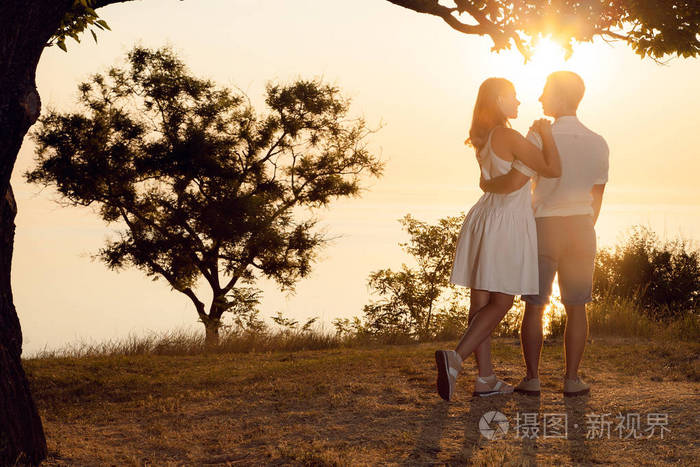 这对夫妇站在沙滩上一个男人和一个女人在拥抱关系和爱一棵树一颗心的