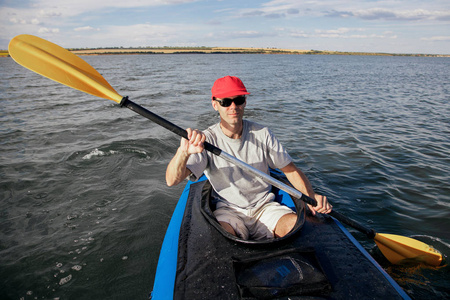 一个人在独木舟上漂浮在湖面上。在水上运动。运动员拿着桨