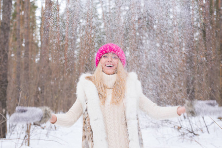 年轻漂亮的妇女投掷雪在空气中的冬季假期
