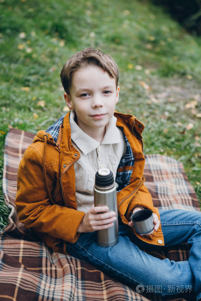 可爱的男孩走在一个五颜六色的秋天公园和姿势.