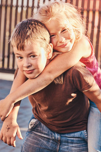 快乐的小朋友们在院子里玩的肖像。男孩抱着女孩在他的背上