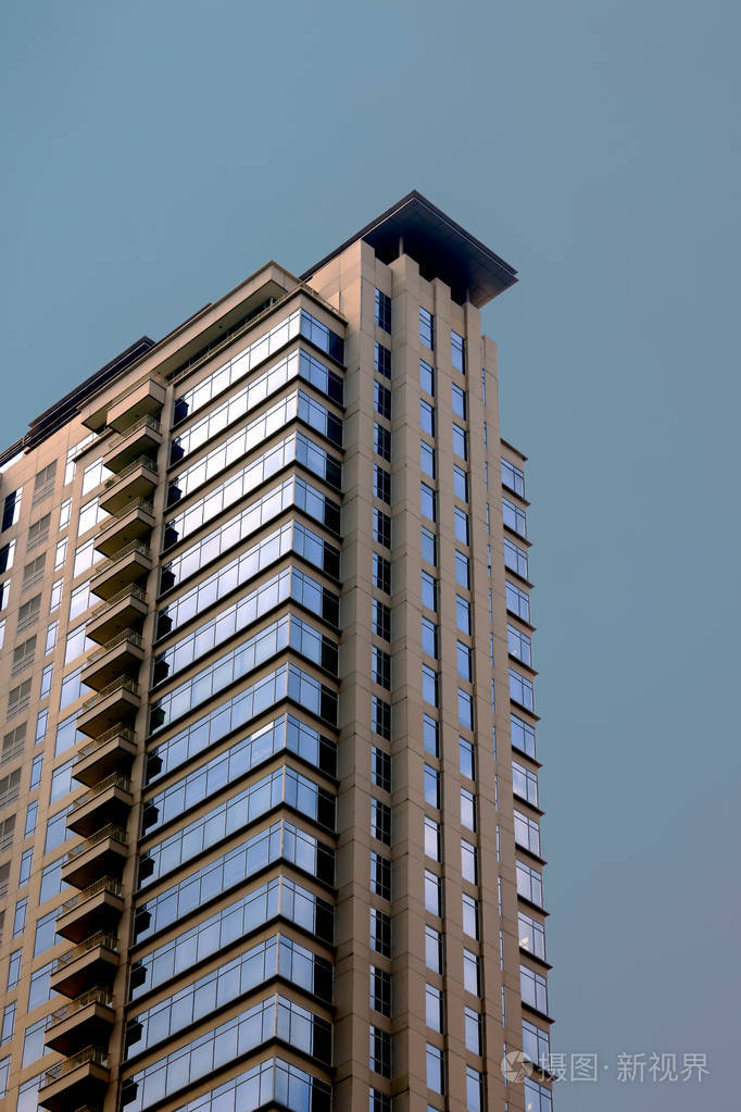 玻璃窗口建筑以人为蓝天颜色作为背景.大厦有大约二十层高度