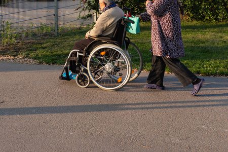 资深夫妇与轮椅在户外公园在德国南部春天历史城市阳光明媚的晚上
