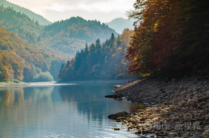 在山湖上的秋季风景。山毛榉树的黄叶在水中反射