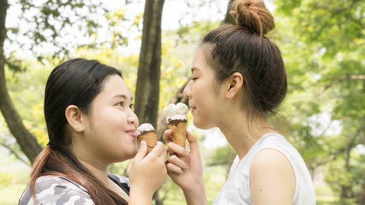 两个人胖可爱的女孩吃冰淇淋与感觉美味