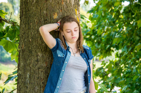 忧郁的少女倚在树上