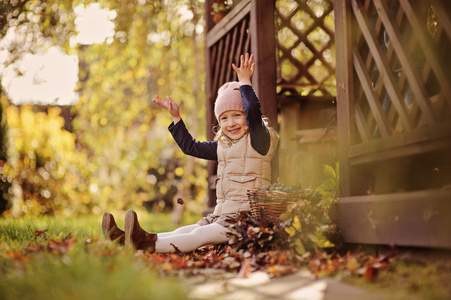 可爱的快乐儿童女孩玩和投掷叶在阳光明媚的秋天的花园
