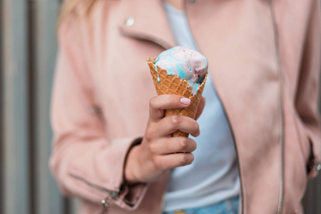 美味的粉红色和蓝色冰淇淋。女孩拿着冰淇淋圆锥形