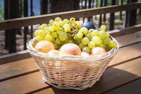 在木桌户外派对或野餐上, 用葡萄桃子和 plumps 的篮子特写