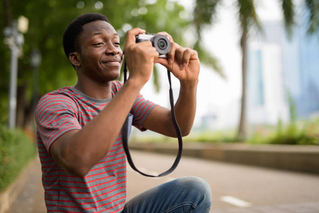 年轻英俊的非洲人拍照与相机在公园
