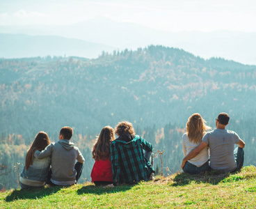一些夫妇的男孩和女孩坐在悬崖上愉快的情绪生活方式概念青年家庭旅行活动冒险假期
