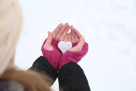 妇女手捧着雪心的羊毛手套.特写照片