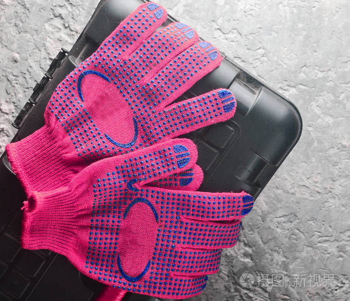 橙色工作手套在一个工具箱上的灰色混凝土背景顶部视图