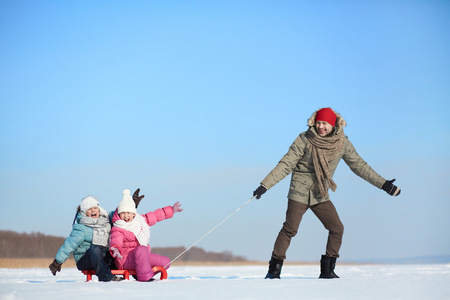 孩子们坐在雪橇上时他们的父亲