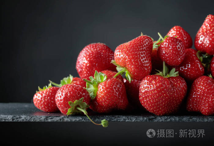 成熟的草莓绿色的叶子在黑色的背景复制空间