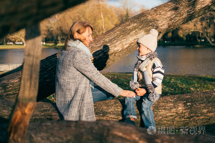 母亲和孩子在湖边的秋季公园拥抱.