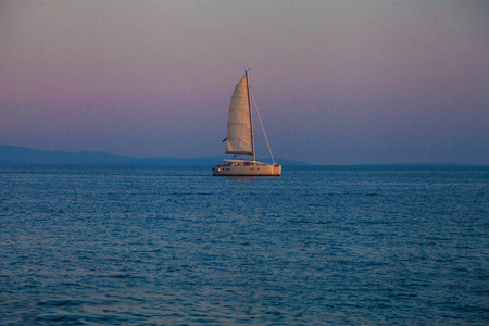 Catamatan 游艇航行在平静的海面上日落的光线