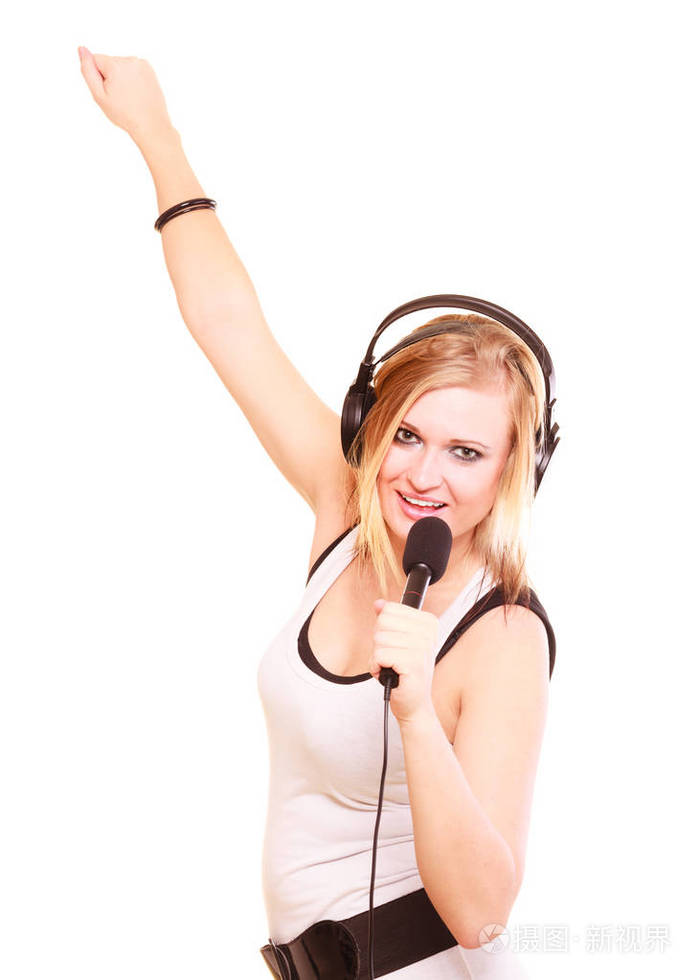 金发碧眼的年轻女子到麦克风唱歌和表演歌曲和开心,她头上戴着大耳机